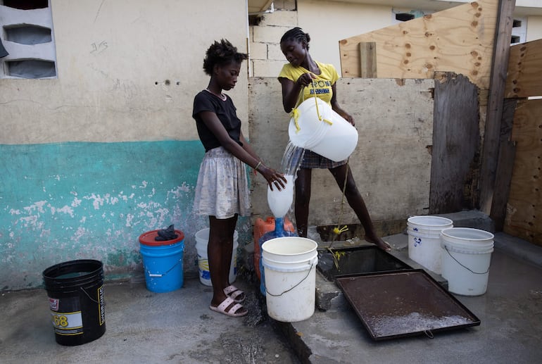 Dos jóvenes sacan agua de un pozo en el campamento de refugiados Carrade, este sábado en Puerto Príncipe (Haití). 