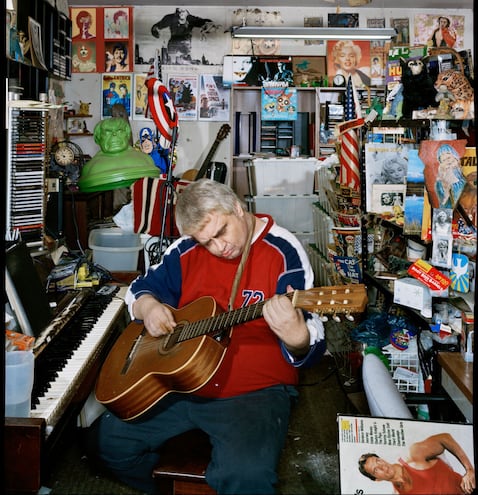 Daniel Johnston rodeado de varios de los personajes y elementos de su propio imaginario mítico y artístico en el garaje de la casa de sus padres en noviembre del 2004. Fotografía de Dan Winters.