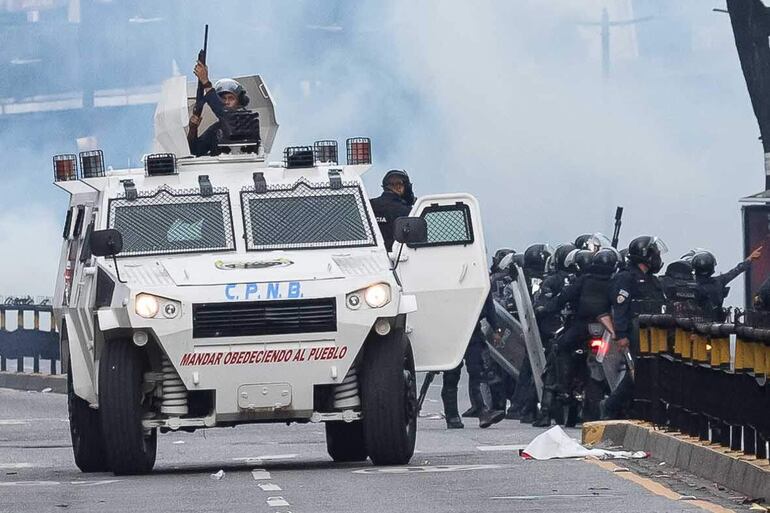 Integrantes de la Policía Nacional Bolivariana (PNB) enfrentan a manifestantes opositores este lunes, durante una protesta contra de los resultados de las elecciones presidenciales, en Caracas (Venezuela).