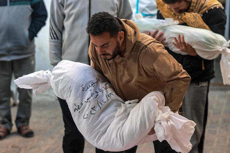 Un hombre en un hospital en Rafah, en el sur de la Franja de Gaza, lleva en brazos el cuerpo de un niño fallecido durante un bombardeo israelí, el pasado martes.