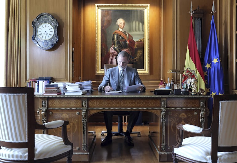 El rey Felipe VI sentado en su despacho del Palacio de la Zarzuela  revisando unos papeles mientras hace algunas anotaciones. (EFE/Casa de S. M. el Rey)
