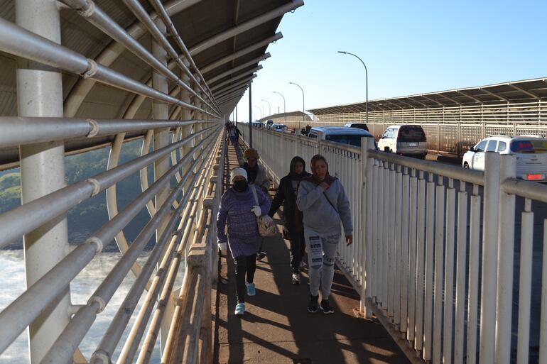 Un grupo de personas cubiertas de ropa de inverno transita sobre el paso peatonal del Puente de la Amistad, ante el clima frío encima del río Paraná.