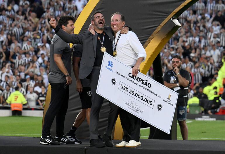 US businessman and owner of Botafogo's SAF, John Textor, holds a check for US$23 million as he celebrates with Portuguese head coach Artur Jorge during the award ceremony of the Copa Libertadores final football match between Brazilian teams Atletico Mineiro and Botafogo at the Mas Monumental Stadium in Buenos Aires on November 30, 2024. (Photo by Luis ROBAYO / AFP)