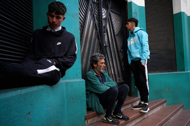 Personas en situación de calle aguardan la apertura de un refugio nocturno en Montevideo. (AFP)