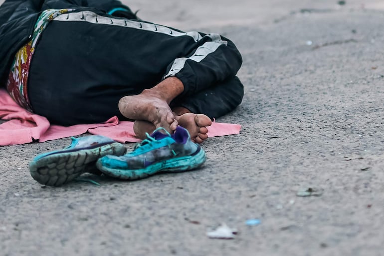 Fotografía de una persona en situación de calle en Buenos Aires (Argentina). Jonathan Gómez barre la acera afanosamente, acomoda su colchón y enciende un brasero para matar el frío en una calle de la capital argentina, donde la indigencia se duplicó en un año mientras más de la mitad de la población del país es pobre.