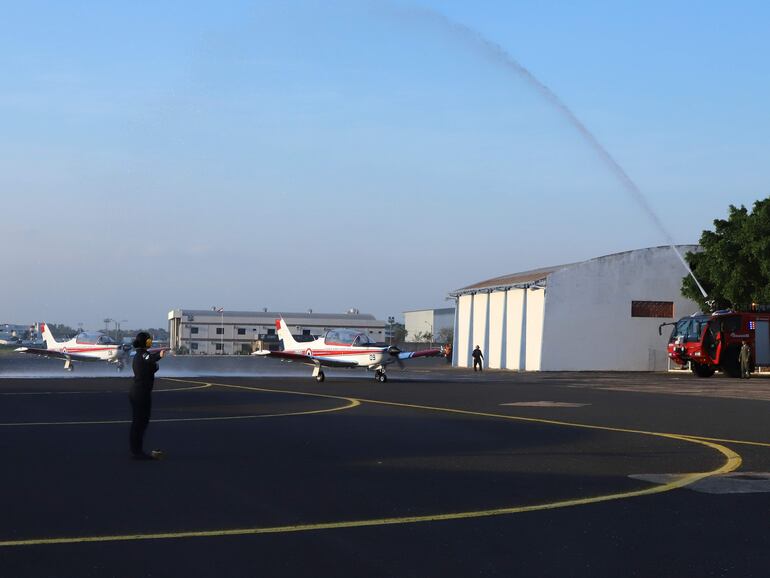 Un vigoroso chorro de agua se eleva por sobre la pista de la I Brigada Aérea de la Fuerza Aérea Paraguaya y “bautiza” a las dos aeronaves paraguayas T35 Pillán que regresaron desde el hangar de la Fuerza Aérea de Chile.