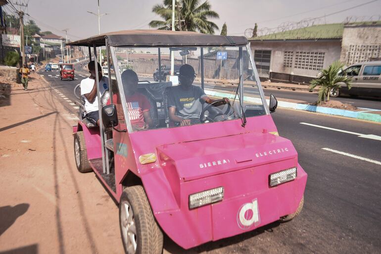 El innovador autodidacta James Samba (derecha) conduce un vehículo eléctrico ecológico que fabricó con metales reciclados en Freetown. 