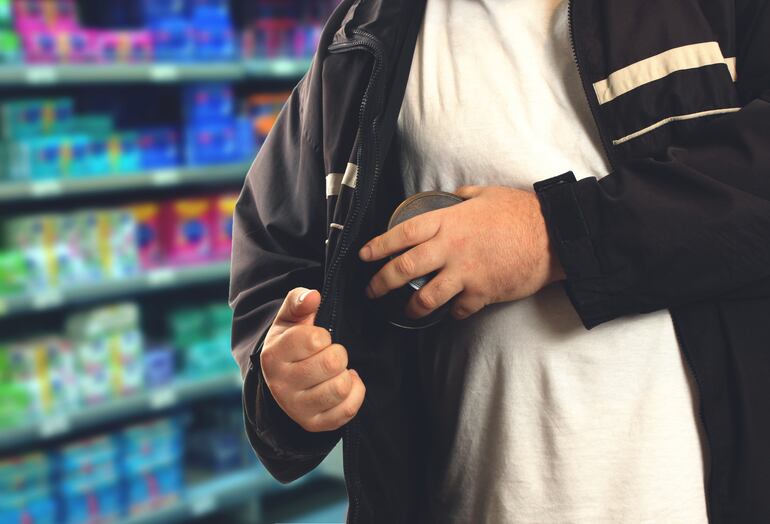 Un hombre sustrae un producto de una tienda.