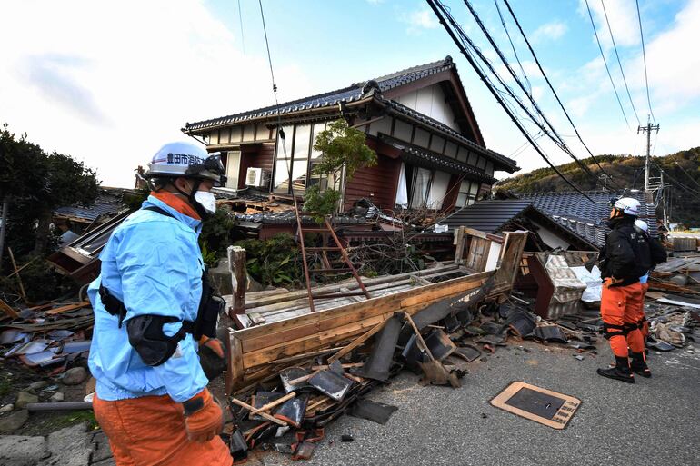 Bomberos inspeccionan los escombros de una casa colapsada en Wajima, en la prefectura japonesa de Ishikawa, este martes.