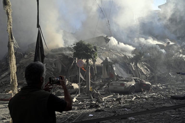 Un hombre toma una fotografía del sitio de un bombardeo israelí, este jueves en un suburbio de Beirut, Líbano.