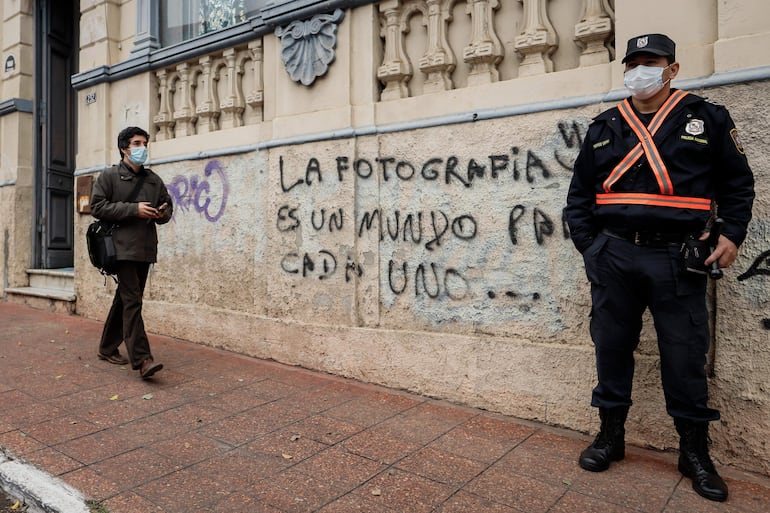 Un policía hace guardia junto a un grafiti alusivo a la fotografía, en Asunción.