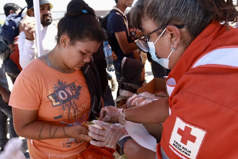 Una voluntaria de la Cruz Roja reparte alimentos a migrantes hoy, en Ciudad Juárez, Chihuahua (México).