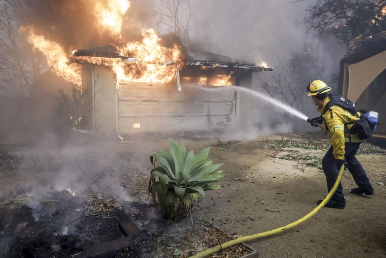 Un bombero del condado de Los Ángeles intenta apagar el fuego de una estructura en llamas durante el incendio forestal de Eaton en Altadena, California, EE.UU., el 08 de enero de 2025.