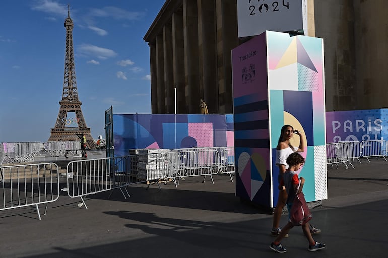 Los peatones pasan junto a las vallas que cierran el acceso al Trocadero con la Torre Eiffel al fondo antes de los Juegos Olímpicos y Paralímpicos de París 2024, en París.