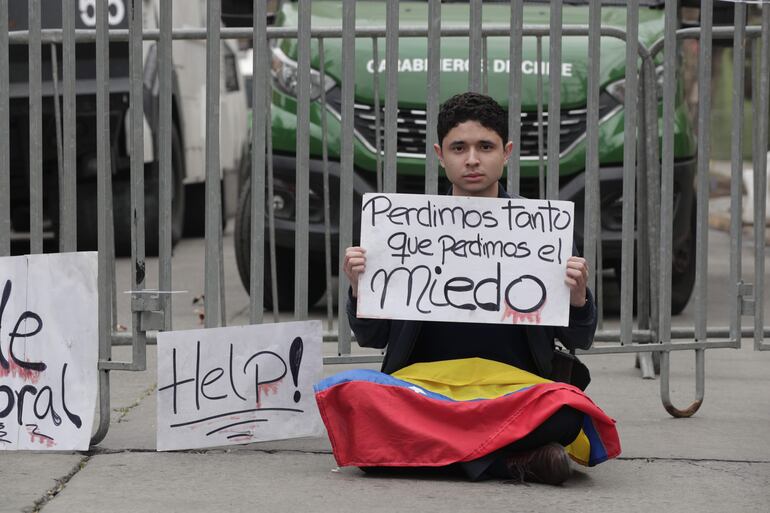 Un ciudadano venezolano sosteniendo un cartel afuera de la embajada de Venezuela,en el barrio de Providencia en Santiago (Chile). Los ciudadanos que necesitan hacer distintos trámites llegaron a la sede de la embajada para preguntar sobre el cierre de la misión diplomática anunciada el martes por el Gobierno de Nicolás Maduro.