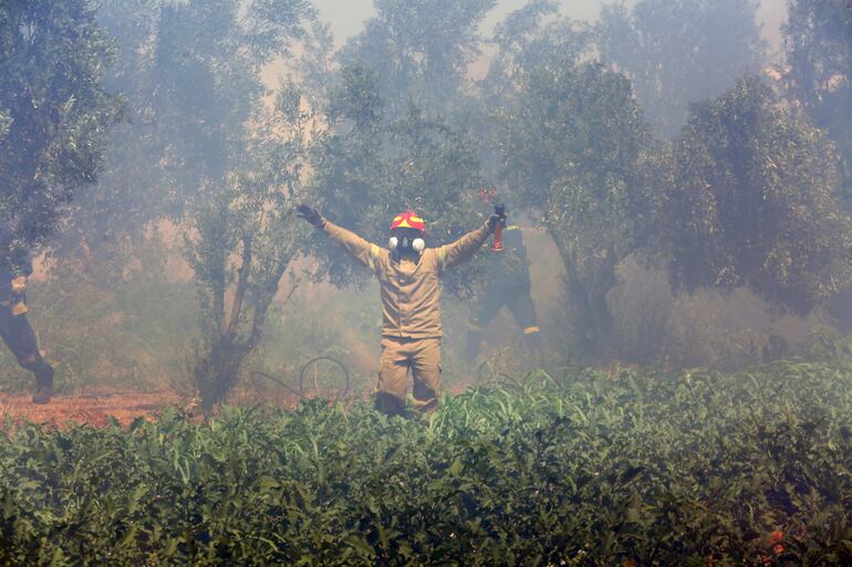 Bomberos trabajan para frenar los incendios forestales en la histórica ciudad de Maratón.