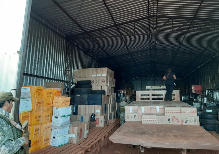 Los intervinientes revisan uno de los cinco depósitos encontrados dentro del predio allanado, en cuyo interior hallaron centenares de cajas con cigarrillos de distintas marcas  tabacaleras.