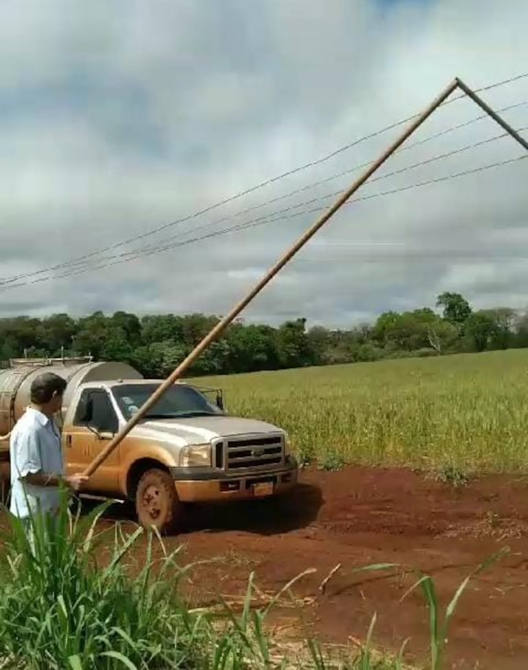 Tambero sosteniendo manualmente el tendido eléctrico que obstruye el paso en un camino vecinal, en la colonia Las Mercedes.