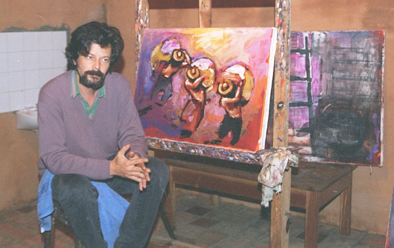 Koki Ruiz en una fotografía del año 1998, en su taller, junto a una de sus obras en la que ilustra a los cosecheros.