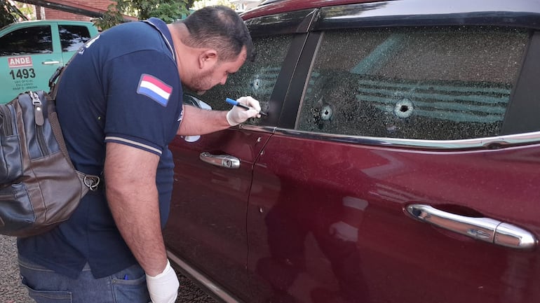 Un oficial de policía verifica los orificios de bala en la camioneta de Mario Aníbal Escobar (funcionario de la Ande), en Pedro Juan Caballero.