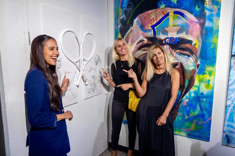 Lili Cantero (izquierda) en compañía de visitantes a la muestra, con una de sus obras.