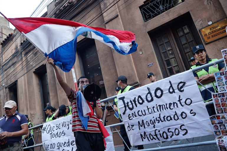 Un hombre protesta frente a la sede del Jurado de Enjuiciamiento de Magistrados. Organizaciones paraguayas protestaron y exigieron la prisión para las personas presuntamente vinculadas con una supuesta trama de corrupción en la Justicia paraguaya, al parecer relacionada con "favores" y "ofrecimiento de dinero" entre legisladores, fiscales y una jueza. EFE/ Juan Pablo Pino