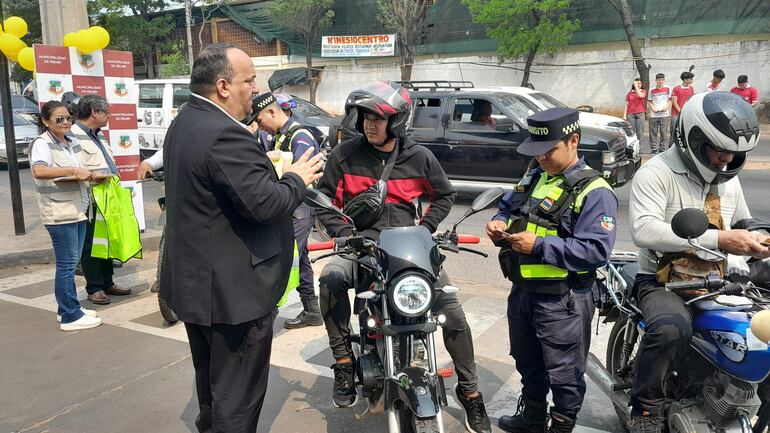 El director de Tránsito de la Municipalidad de Ñemby, Edgar Franco, ofrece una charla a un motociclista antes de obsequiar el chaleco reflectivo.