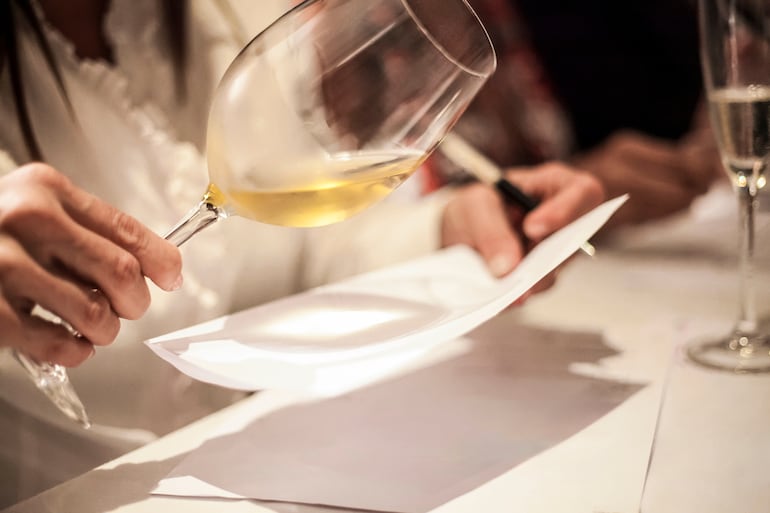 Una sommelier toma notas de cata de un vino blanco.