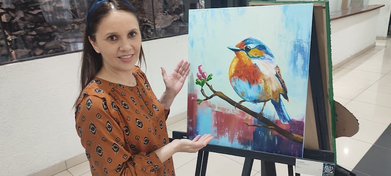 Deolinda Bordón, artista integrante del colectivo Aty Guazú, con una de sus obras expuestas en la muestra que desarrolla en el Centro Social de Encarnación, y culmina mañana.