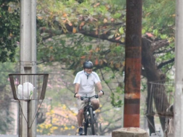 Un hombre circula en bicicleta por una calle de Asunción, a la sombra de los árboles.