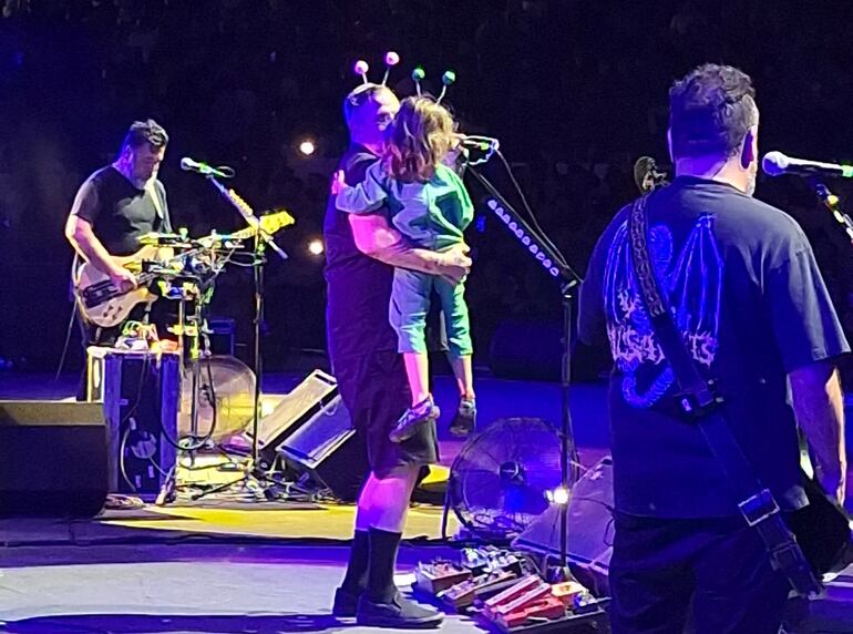 Randy Ebright, baterista de Molotov, con su hijo Elio en brazos en el escenario del anfiteatro José Asunción Flores.