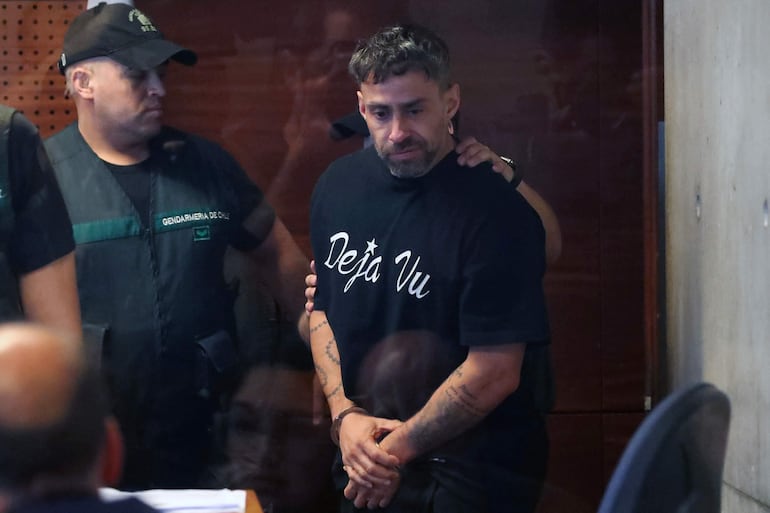 In this photo released by Aton Chile, former Chilean footballer Jorge Valdivia, idol of Brazilian club Palmeiras and Chile's Colo Colo is guarded by police officers after being arrested after a rape complaint was filed against him, in Santiago on October 22, 2024. Former Chilean international footballer Jorge Valdivia, who was placed in preventive detention on October 22, 2024, after a rape complaint was filed against him, faces a second charge for the same offence, prosecutors said on October 23. (Photo by Jonnathan OYARZUN / ATON CHILE / AFP) / Chile OUT / RESTRICTED TO EDITORIAL USE