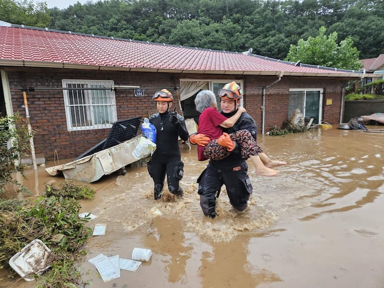 Rescatistas trasladan a una mujer de una zona inundada en el condado de Wanju, Corea del Sur, este miércoles.