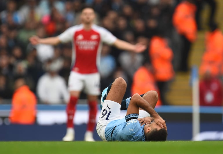 El español Rodri, jugador del Manchester City, cae al suelo producto de una lesión en el partido frente al Arsenal por la quinta fecha de la Premier League 2024-2025 en el Etihad Stadium, en Mánchester, Inglaterra.