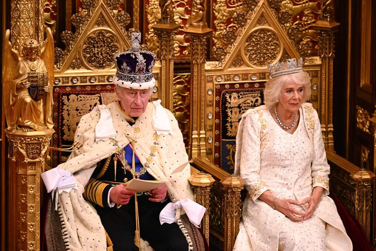 El rey Carlos III de Gran Bretaña, con la corona imperial y la túnica de Estado, se sienta junto a la reina Camilla de Gran Bretaña, con la diadema estatal de Jorge IV, mientras lee el discurso del rey desde el Trono del Soberano en la cámara de la Cámara de los Lores, durante la inauguración estatal del Parlamento, en las Casas del Parlamento, en Londres. (Leon Neal / POOL / AFP)