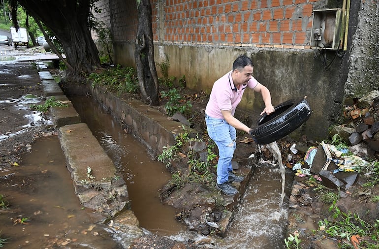 Derlis Solís saca un neumático de la canaleta de desagüe. 