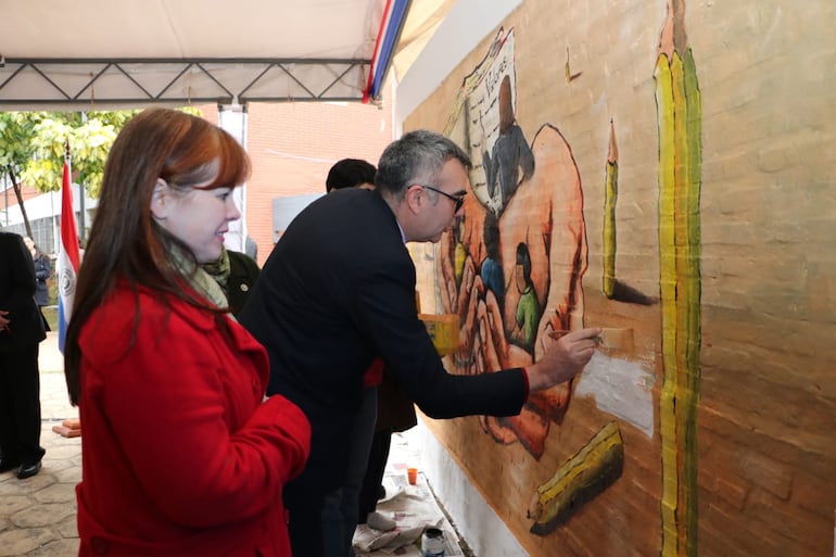 El ministro de Educación, Nicolás Zárate, pinta un mural en el colegio nacional Naciones Unidas. La viceministra de Educación, Alcira Sosa, lo acompaña.