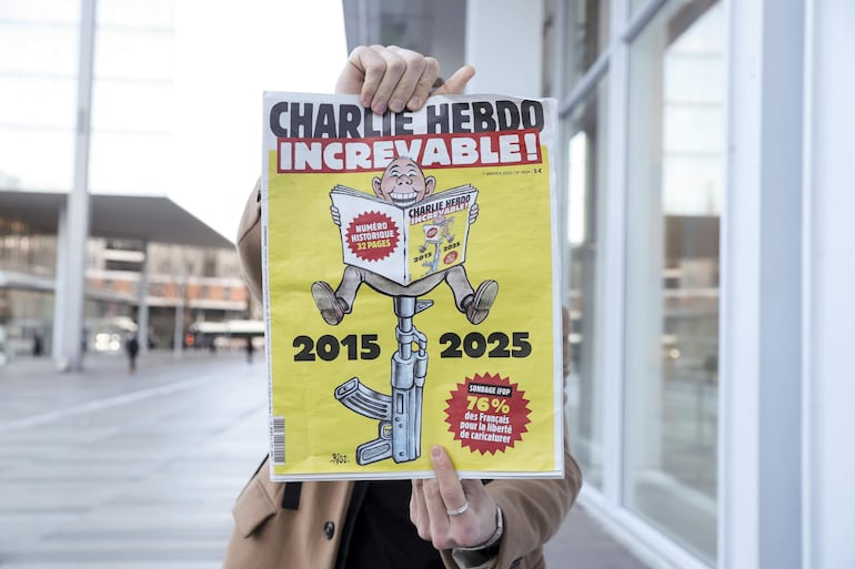 Una persona sostiene la edición especial de la revista satírica Charlie Hebdo lanzada por el aniversario del atentado en que 12 de sus empleados fueron asesinados en enero de 2015.