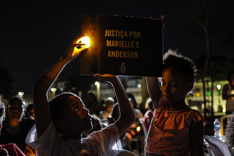 Una pareja de jóvenes sostiene un cartel durante un acto para exigir el esclarecimiento del asesinato de Marielle Franco hoy, en Río de Janeiro (Brasil).