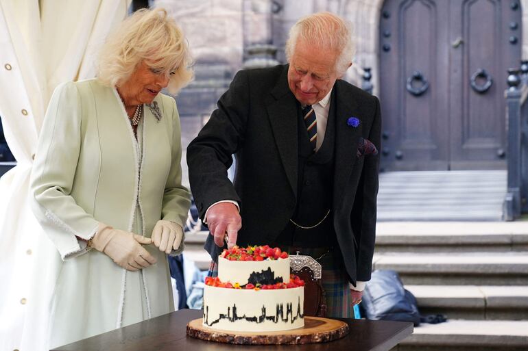 El rey Carlos III de Gran Bretaña junto a la reina Camila corta un pastel hecho por el ganador del Great British Bake Off 2020, Peter Sawkins, durante la celebración del 900 aniversario de la ciudad de Edimburgo.