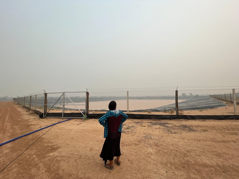 Una nativa observa un tajamar con la membrana para la acumulación de agua.