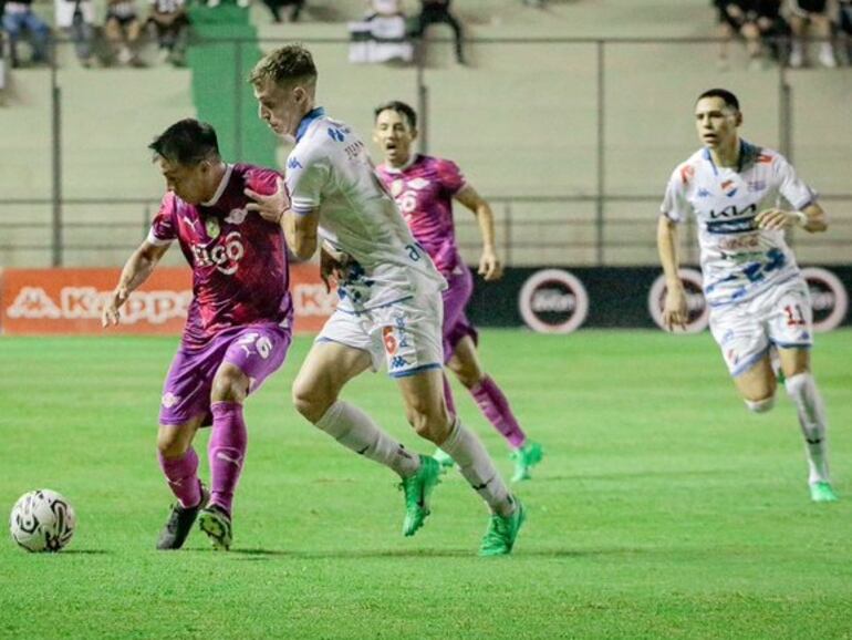 Ángel Cardozo Lucena (i), jugador de Libertad, pelea por el balón en un partido frente a Nacional por la regularización de la octava jornada del torneo Apertura 2024 del fútbol paraguayo en el estadio Arsenio Erico, en Asunción, Paraguay.