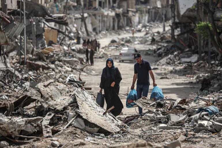 Dos personas caminan entre escombros de edificios destruidos en Jan Yunis, en el sur de la Franja de Gaza.