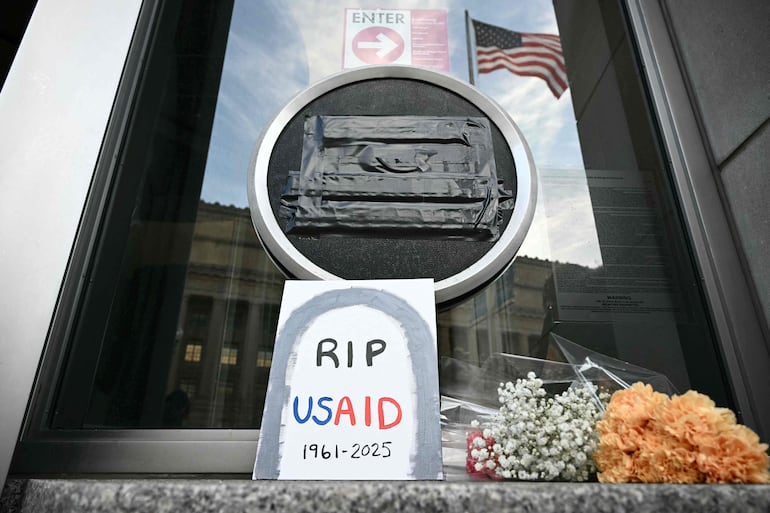 Homenajes son colocados bajo el sello cubierto de la Agencia de los Estados Unidos para el Desarrollo Internacional (USAID) en Washington, DC, el 7 de febrero de 2025. El presidente de EE.UU., Donald Trump, pidió el 7 de febrero de 2025 el cierre de USAID, intensificando su inédita campaña para desmantelar la agencia humanitaria.