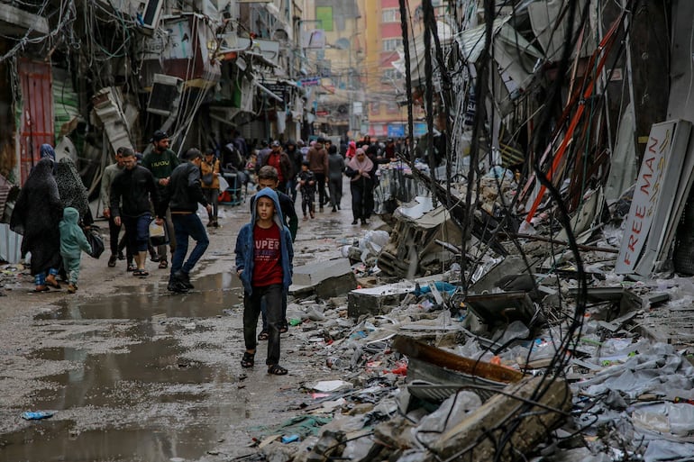 Palestinos caminan entre los escombros de edificios destruidos por bombardeos israelíes en la Ciudad de Gaza, el lunes.