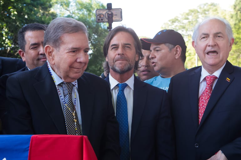 El líder opositor venezolano Edmundo González Urrutia (i) escucha a simpatizantes junto al presidente de Uruguay, Luis Lacalle Pou (c), en Montevideo (Uruguay). González Urrutia agradeció a Lacalle Pou "por haber sido solidario" con la causa de su país y aseguró a la gente que lo acompañó en Montevideo que se logrará la recuperación de Venezuela. 