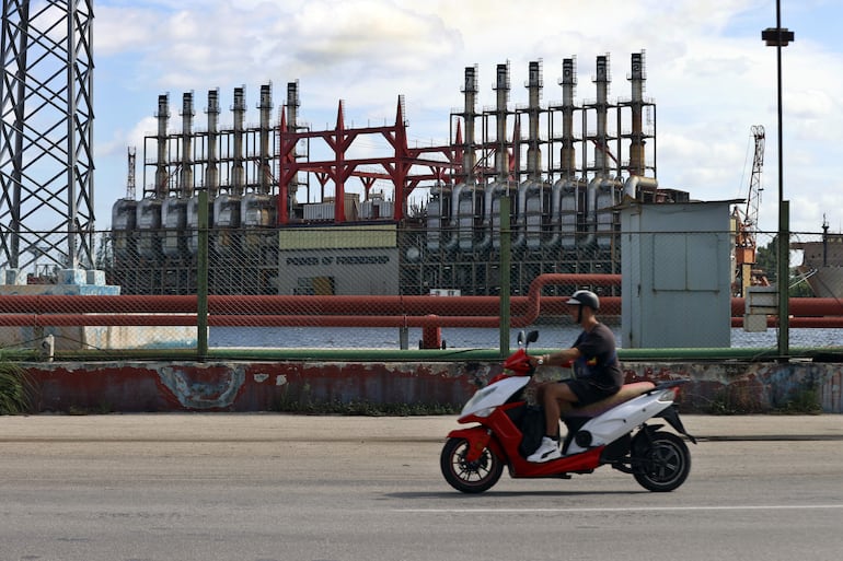 Un hombre en una moto eléctrica pasa frente a una de las plantas de generación eléctrica que permanece este domingo, en el puerto de La Habana (Cuba). El ministro de Energía y Minas de Cuba, Vicente de la O Levy, reconoció este domingo que se han registrado algunos "incidentes mínimos" a raíz del apagón masivo que afecta al país desde hace más de 48 horas, pero cargó duramente contra quienes han protestado.