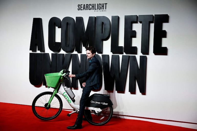 Timothée Chalamet posando con la bicicleta en la red carpet londinense de "A Complete Unknown". (BENJAMIN CREMEL / AFP)