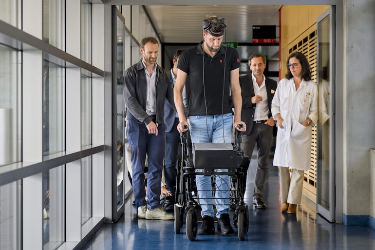 El paciente parapléjico neerlandés Gert-Jan (C) camina gracias a la Interfaz Cerebro-Computadora (BCI, por sus siglas en inglés), que permite caminar controlando los movimientos con el pensamiento tras una lesión en la médula espinal, durante una conferencia de prensa en Lausana, Suiza. (archivo)