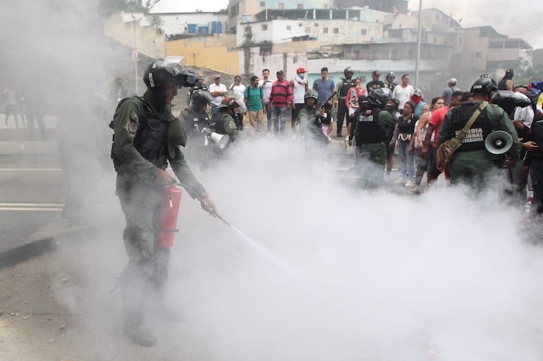 Un integrante de la Guardia Nacional Bolivariana (GNB) extingue el fuego de neumáticos quemados por manifestantes luego de los resultados de las elecciones presidenciales hoy, en el sector del Primero de Mayo en Caracas (Venezuela).